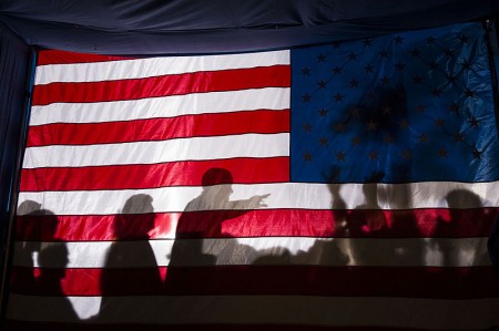 Barack Obama silhouetted behind a flag - Public Domain